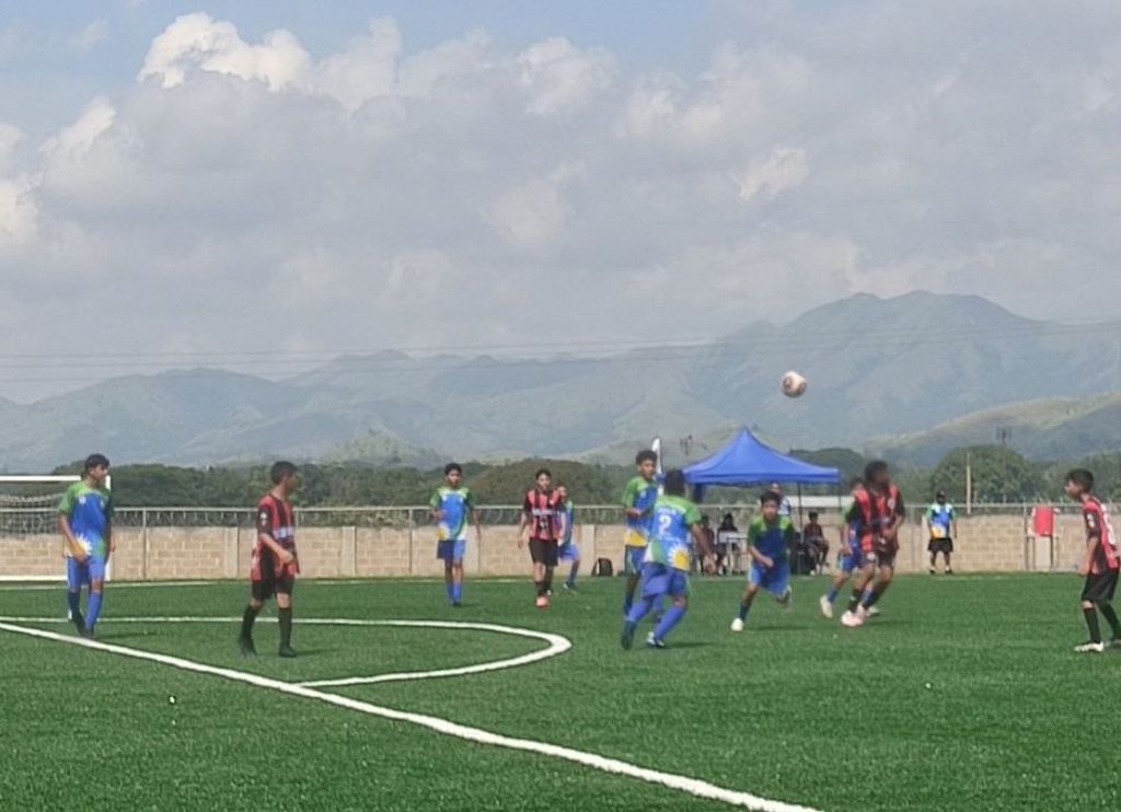 Las instalaciones de la Universidad Nacional de las Comunas (Unacom), ubicadas en el estado Carabobo, albergaron los encuentros de las categorías Sub-12 y Sub-14 de la Copa Libertador Tricolor Venezuela 2026. Esta cita deportiva, organizada mediante el Vicerrectorado para la Democracia y Sociedad Comunal junto a la viceministra y vicerrectora Kelly Pacheco, en alianza con la Asociación Nacional Liga de Fútbol de Desarrollo, reunió a 28 equipos provenientes de siete estados del país para consolidar la masificación del deporte y la integración de la juventud comunal.